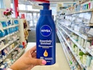 a hand holding a bottle of body lotion in a store aisle 
