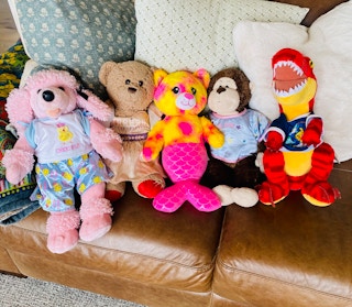 five different build-a-bears next to each other on a couch