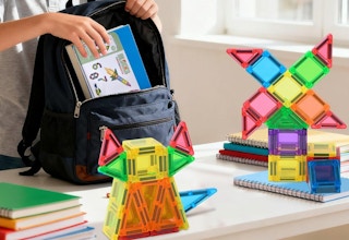 a kid packing a backpack on a table with magnetic tiles