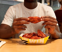 Man holding a chicken wing while doing the Buffalo Wild Wings Blazin Challenge food challenge