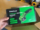 man using electric scissors on cardboard
