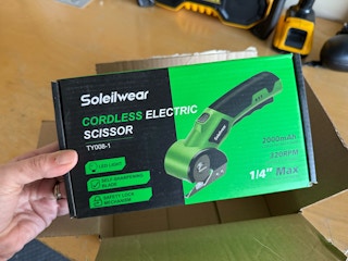 man using electric scissors on cardboard