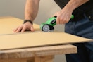 man using electric scissors on cardboard