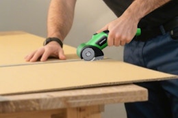 man using electric scissors on cardboard