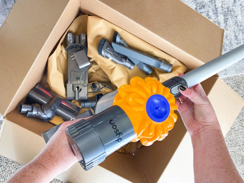 someone looking at a refurbished vacuum out of a box