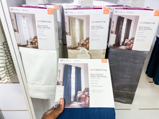 a person holding a pack of curtains front of the curtains section