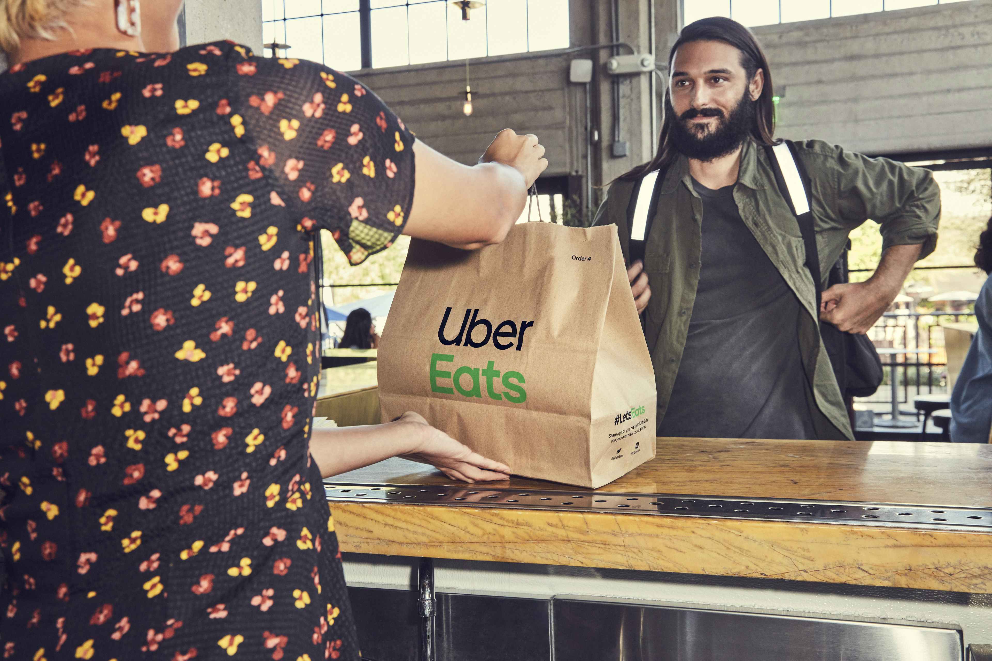an Uber Eats delivery person picking up an order from a restaurant