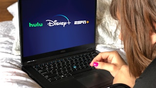someone looking at laptop with Disney plus hulu and espn
