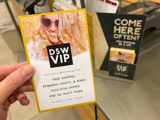 A person holding up a DSW VIP info card near checkout.