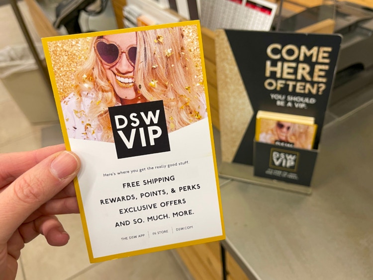 A person holding up a DSW VIP info card near checkout.