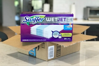 A container of Swiffer WetJet refills on top of an open Amazon box.