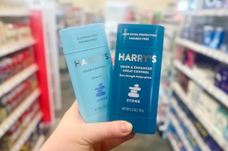 person holding 2 harrys deodorants in an aisle