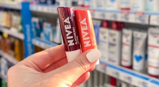 hand holding two tubes of nivea lip balm in a store