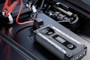 Car battery jump starter sitting on a car battery.
