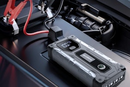 Car battery jump starter sitting on a car battery.