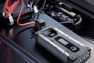 Car battery jump starter sitting on a car battery.