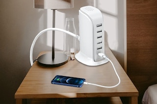 A smartphone on a nightstand plugged in to a charging station