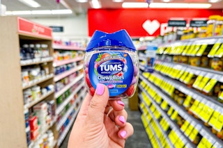 person holding a container of tums chewy bites in an aisle