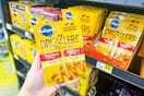 hand holding pedigree drizzlers dog food in front of dollar general shelf