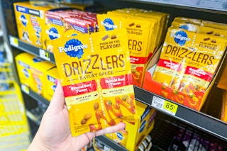 hand holding pedigree drizzlers dog food in front of dollar general shelf