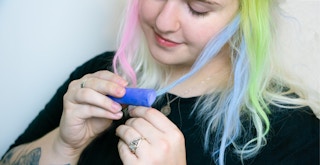 someone using some sidewalk chalk to color their hair blue