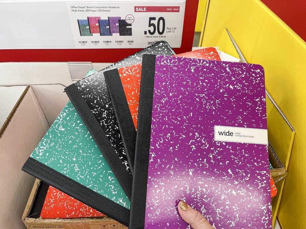 Someone holding up some composition notebooks in Office Depot
