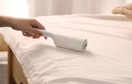 a person using a lint roller on bedding 