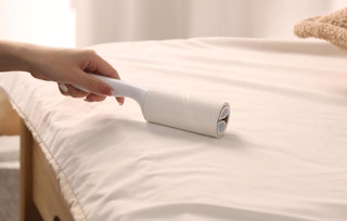 a person using a lint roller on bedding