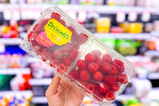 hand holding a container of raspberries in produce at target