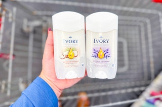 person holding two ivory deodorants over a cart