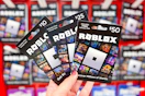hand holding Roblox gift cards in front of the gift card area at Target