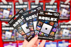hand holding Roblox gift cards in front of the gift card area at Target