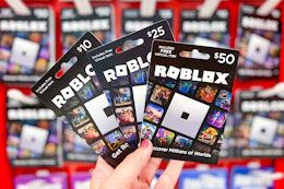 hand holding Roblox gift cards in front of the gift card area at Target