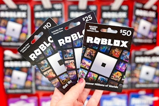 hand holding Roblox gift cards in front of the gift card area at Target