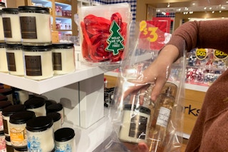 A woman in Bath & Body Works, packaging her candles and fragrance into a plastic gift bag.