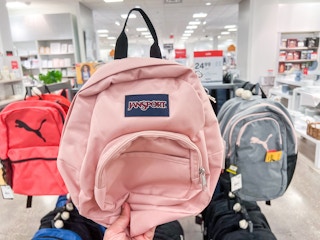 someone holding a light pink jansport backpack