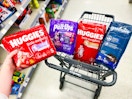 hand holding huggies diaper pack with more in a shopping cart