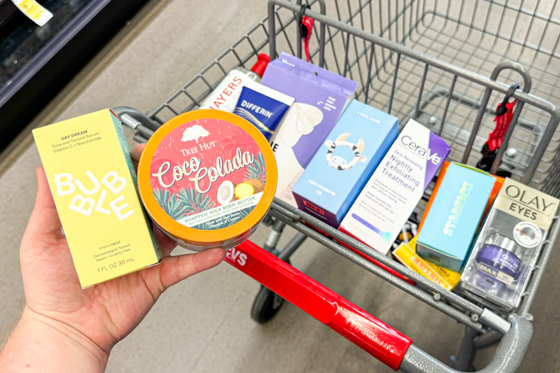 person holding bubble and tree hut skincare over a cart with more skincare products in it