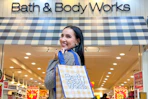 a woman holding a bath and body works bag outside the store 