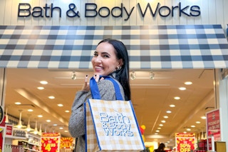 a woman standing in front of bath and body works holding a bag