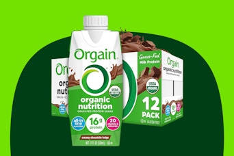 A 12-pack of Orgain Organic Protein Shakes with 16g protein in creamy chocolate fudge flavor with one large carton in front of the case.