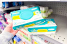 person picking up pampers baby wipes from a shelf
