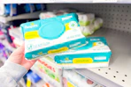 person picking up pampers baby wipes from a shelf