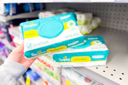 person picking up pampers baby wipes from a shelf