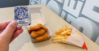 a person holding a big mac sauce cup in front of nuggets and fries at McDonald's