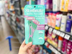 hand holding a pack of skintimate razors in walmart aisle