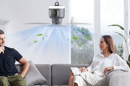 two people sitting on a couch under a fan