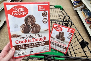 person holding a box of betty crocker no bake cookie dough bites over a cart