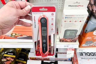 hand holding a thermopro thermometer in front of a target shelf
