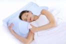 A woman lies on her side while using the 2-in-1 cooling cervical memory foam neck pillow.